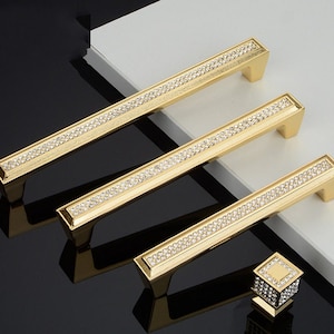 May include: Three gold cabinet pulls with a row of clear rhinestones. A matching gold knob with rhinestones is also shown.