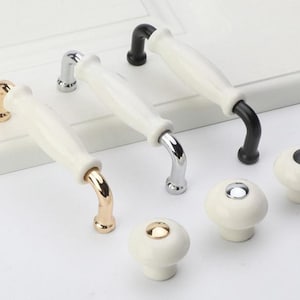 May include: Five white ceramic cabinet knobs with different metal finishes: gold, silver, and black. The knobs have a mushroom-shaped base and a long, slender handle.