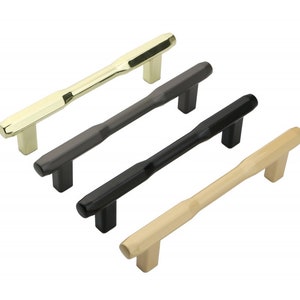 May include: Four cabinet pulls in different finishes: gold, black, gray, and beige. Each pull has a rectangular shape with a slightly curved design.