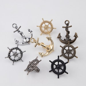 Pode incluir: Conjunto de botões de armário com tema náutico em acabamentos prata, ouro e bronze. Os botões apresentam designs de âncora e roda de navio.