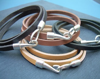 May include: Three leather bracelets with silver hook clasps. The bracelets are layered in brown, tan, and black.