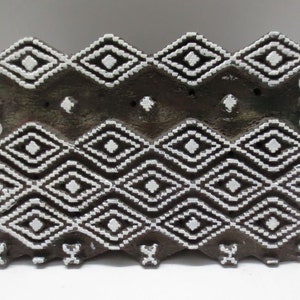 May include: A wooden printing block with a white diamond pattern. The block is used for creating fabric designs.