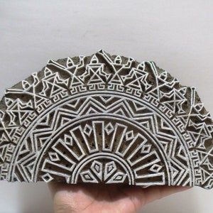 May include: A wooden printing block featuring an intricate white mandala design. The block is carved in the shape of a semi-circle.