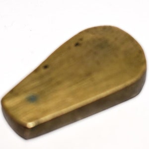 May include: A brass, teardrop-shaped, smooth, solid object with a slightly rounded edge.