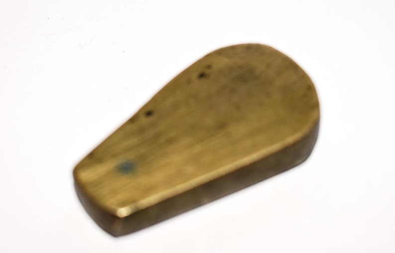 May include: A brass, teardrop-shaped, smooth, solid object with a slightly rounded edge.