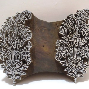 May include: A wooden printing block featuring a floral design. The block is carved with intricate details of flowers and leaves. The block is made of dark wood and has a natural finish.