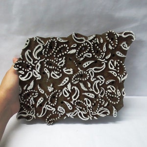 May include: A wooden printing block featuring a white paisley design. The block is used for creating patterns on fabric.