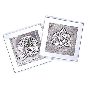 May include: Two silver metal coasters with raised designs. One coaster features a nautilus shell and the other features a Celtic knot.