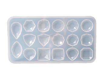May include: A clear, rectangular silicone mold with 15 gemstone-shaped cavities. The cavities are various shapes, including teardrops, hexagons, and squares. The mold is light blue.