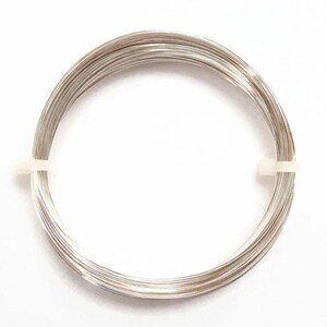 Peut inclure: Une bobine de fil m&eacute;tallique argent&eacute;, dispos&eacute;e en cercle et maintenue par une attache en plastique blanc. Le fil fin et souple est probablement destin&eacute; &agrave; la cr&eacute;ation de bijoux ou &agrave; l'artisanat.