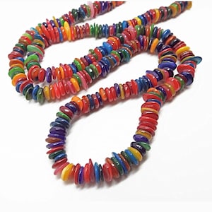 May include: A strand of colourful, flat, round beads made from natural materials. The beads are strung on a clear thread and are arranged in a random pattern. The beads are a variety of colours, including red, orange, yellow, green, blue, and purple.