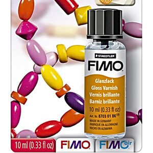 Puede incluir: Una botella de barniz brillante FIMO, 10 ml (0,33 fl oz), con tapa negra. La etiqueta incluye texto en varios idiomas. Cuentas multicolores de varias formas rodean la botella.