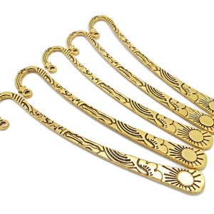 5 gold coloured metal bookmarks in the shape of a shepherds crook with a loop at the top end where beads and charms can be added for decoration.  The bookmark design includes a sun image at the bottom and stars elsewhere.