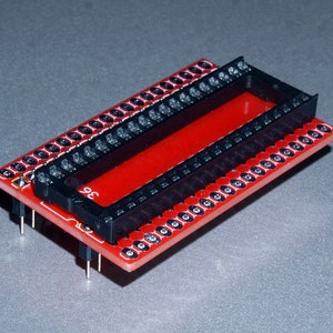 May include: A red and black electronic component with multiple pins and sockets. The component has a rectangular shape with a black socket in the center and a red base. The number "36" is printed on the side.