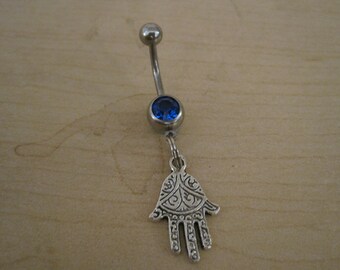 May include: A silver belly button ring with a blue gem and a hamsa hand charm.