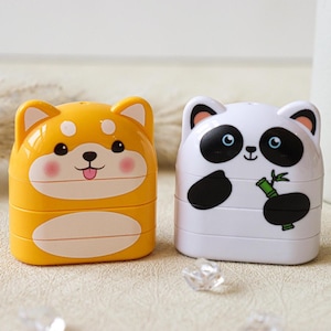 May include: Two small, stackable pencil sharpeners. One is yellow with a cartoon Shiba Inu face and the other is white with a cartoon panda face holding a bamboo shoot.