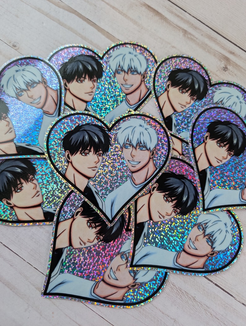 May include: A set of heart-shaped stickers featuring two anime characters. The characters have black and white hair and are depicted in a romantic pose. The stickers are holographic and have a glittery finish.