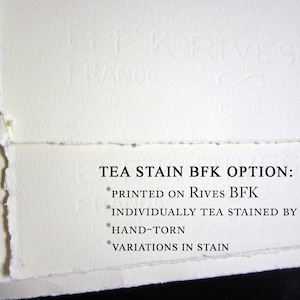 Pu&ograve; includere: Fogli di carta color bianco sporco con bordi strappati a mano e una sottile filigrana in rilievo BFK Rives France. Il testo recita: TEA STAIN BFK OPTION: *PRINTED ON RIVES BFK *INDIVIDUALLY TEA STAINED BY HAND *HAND-TORN *VARIATIONS IN STAIN.