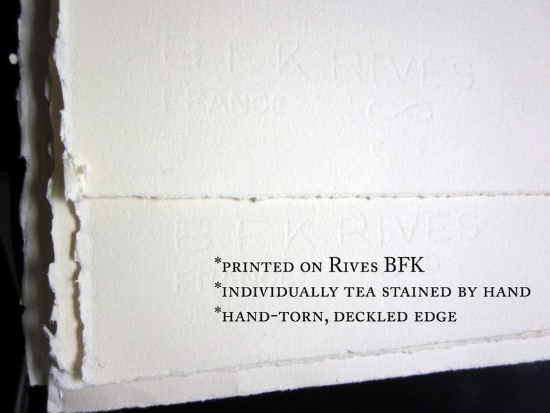 May include: Close-up of the edge of a white paper sheet with a deckled edge. The paper is printed with the text "*PRINTED ON RIVES BFK *INDIVIDUALLY TEA STAINED BY HAND *HAND-TORN, DECKLED EDGE".