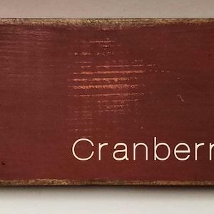 A wooden sign with a red background and the word 'Cranberry' written in white text.
