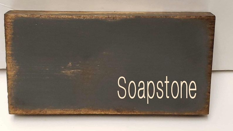 A dark gray wooden sign with the word 'Soapstone' written in white paint.