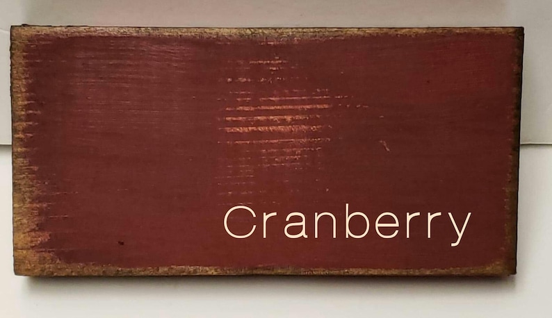A wooden sign with a red background and the word 'Cranberry' written in white text.