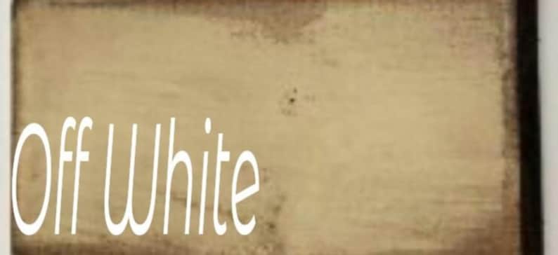 A close-up of a light beige painted wood surface with the text 'Off White' written in white font.