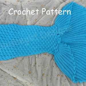 Peut inclure: Patron de crochet pour une couverture en forme de queue de sirène en bleu turquoise avec une bordure violette. La queue est posée à plat sur un fond blanc.