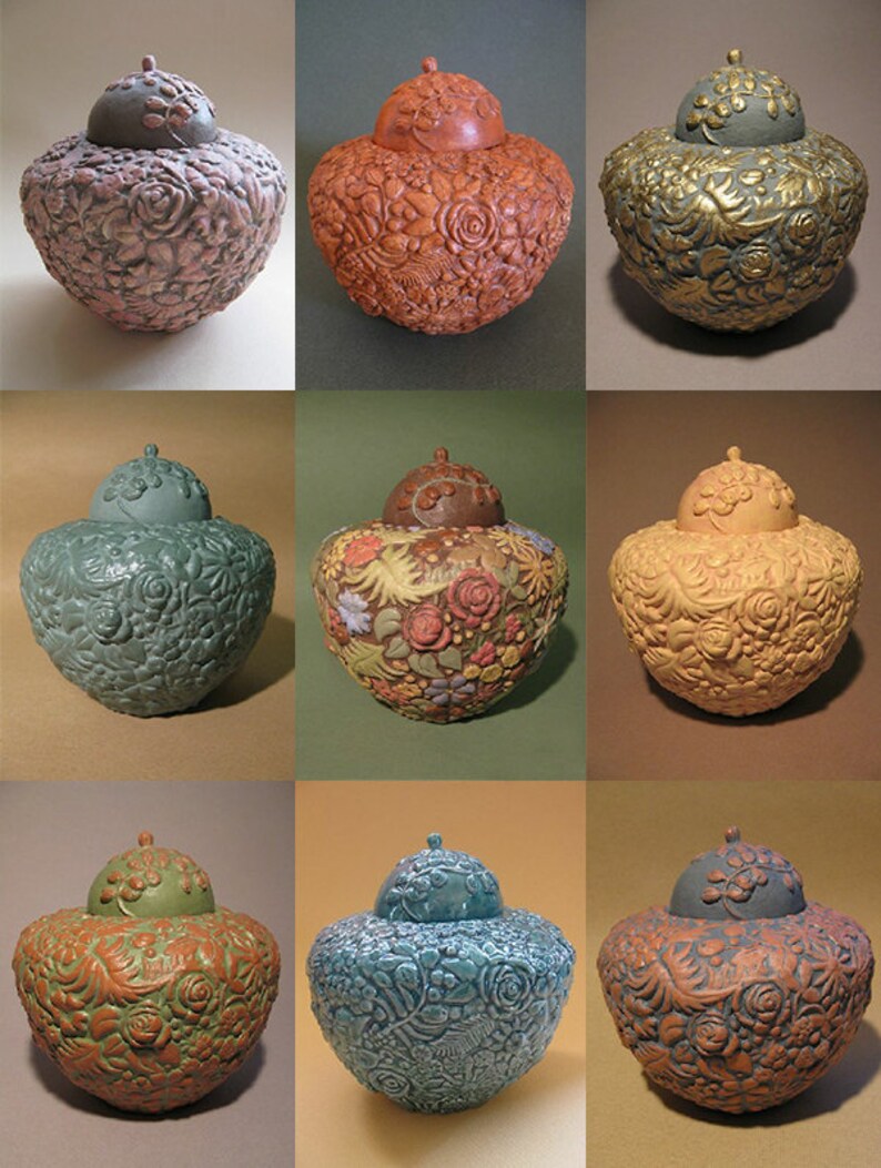 May include: Nine ceramic urns with intricate floral designs in various colors, including pink, orange, green, brown, yellow, and blue. Each urn has a lid with a floral design.