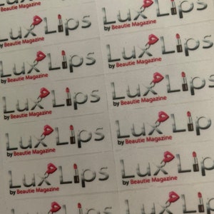 May include: A sheet of white stickers with the text "Lux Lips" and "by Beautie Magazine" repeated multiple times. Each sticker features a pink lipstick graphic.