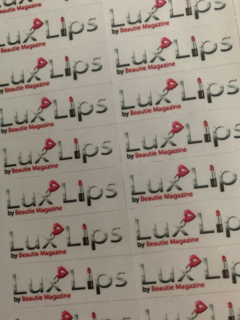 May include: A sheet of white stickers with the text "Lux Lips" and "by Beautie Magazine" repeated multiple times. Each sticker features a pink lipstick graphic.