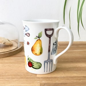Gardening bone china mug with garden tools, vegetables, flowers and ladybirds on the outside.