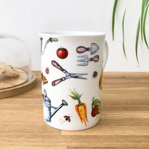 Gardening bone china mug with garden tools, vegetables, flowers and ladybirds on the outside.