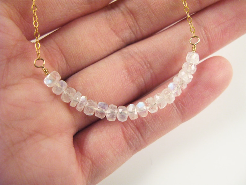 May include: A delicate gold chain necklace with a row of iridescent white moonstone beads.