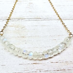 May include: A delicate gold chain necklace with a row of iridescent white moonstone beads.