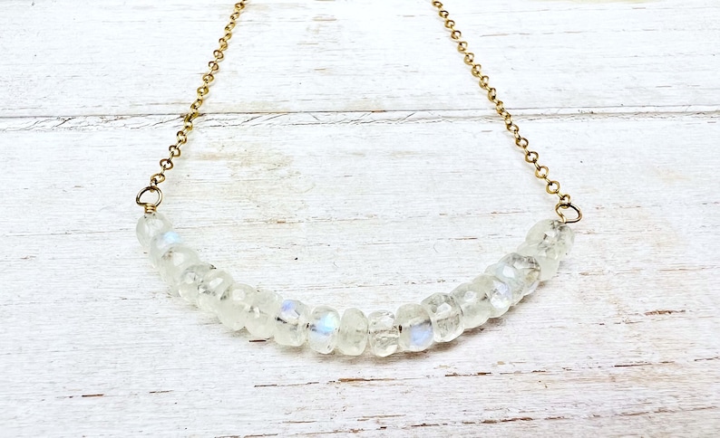 May include: A delicate gold chain necklace with a row of iridescent white moonstone beads.