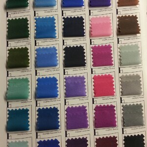 Peut inclure: Un nuancier de couleurs pr&eacute;sentant des &eacute;chantillons de tissu dans diff&eacute;rentes teintes. Les &eacute;chantillons comprennent des couleurs comme le vert &eacute;meraude, le bleu royal et le magenta. Chaque &eacute;chantillon est &eacute;tiquet&eacute; avec un code unique.