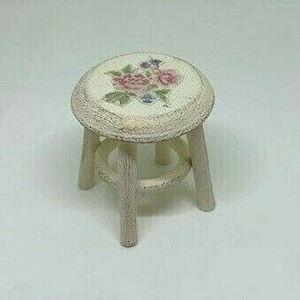 May include: A small, white wooden stool with a floral design on the top. The stool has three legs and a simple, rustic style.