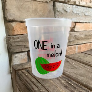 May include: A clear plastic cup with the text "ONE in a melon!" printed on it. The cup has a watermelon graphic on it.