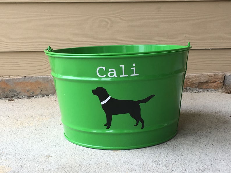 May include: Green metal bucket with the name "Cali" written in white letters and a black silhouette of a dog with a white collar.