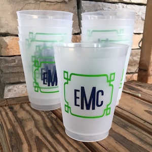 May include: A stack of frosted plastic cups with a green and blue monogram design. The monogram reads "EMC".