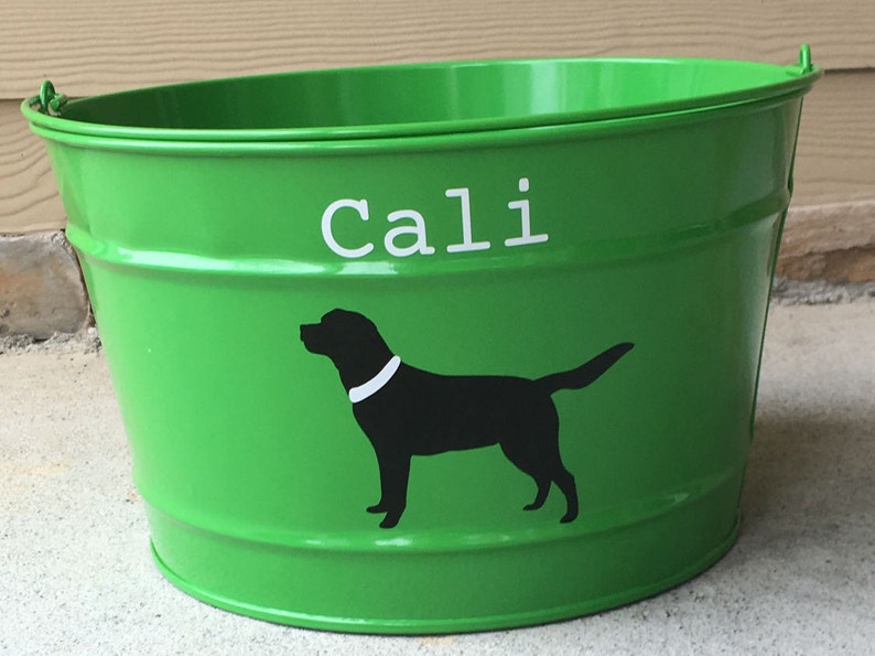 May include: Green metal bucket with a white silhouette of a dog and the name "Cali" written in white letters.