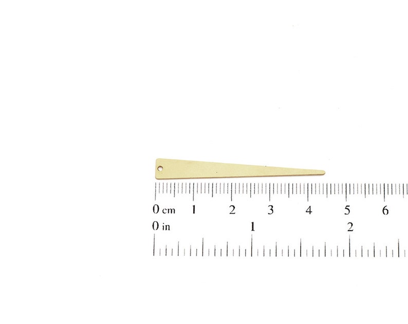 May include: A gold-colored metal triangle with a hole at the top, measuring approximately 4 inches in length. The triangle is shown against a white background with a ruler for scale.