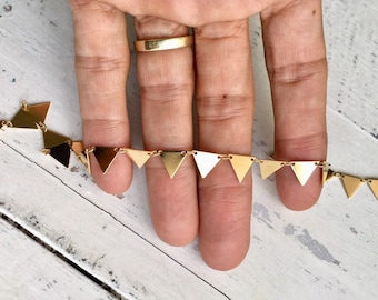 May include: A gold chain necklace with a series of small triangle pendants. The chain is delicate and the triangles are evenly spaced.