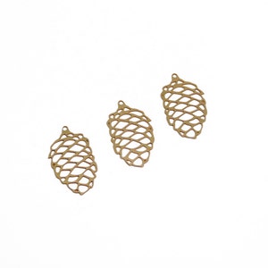 Könnte beinhalten: Drei goldene Metall-Tannenbaum-Anhänger mit einem filigranen, durchbrochenen Design.