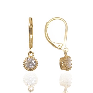 May include: A pair of gold earrings with a clear crystal stone in a gold setting. The earrings have a lever back closure.