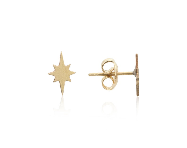 May include: A pair of gold star-shaped stud earrings. The earrings are made of a smooth, shiny metal and have a simple, elegant design.