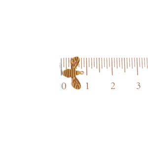 May include: A small, gold-colored bee charm with a striped pattern. The charm is about 1 inch long and is shown next to a ruler.