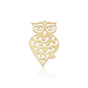 Könnte beinhalten: Ein goldfarbener Metallausschnitt eines Eulen-Anhängers. Die Eule hat ein detailliertes Design mit einem gewellten Muster auf ihrem Körper.