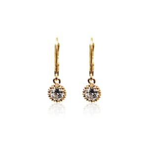 May include: A pair of gold dangle earrings with a small round clear stone set in a gold bezel.